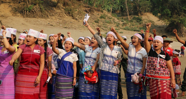 A group of women stand together with their fists raised in protest. 