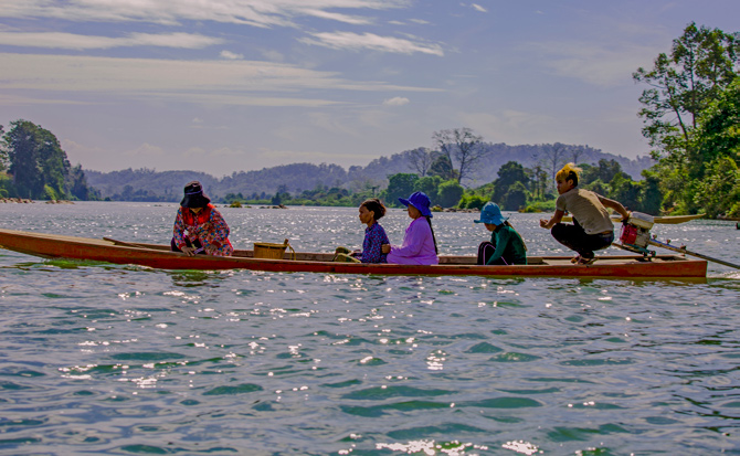 Four women sitting in a boat crossing  the Sesan river. 