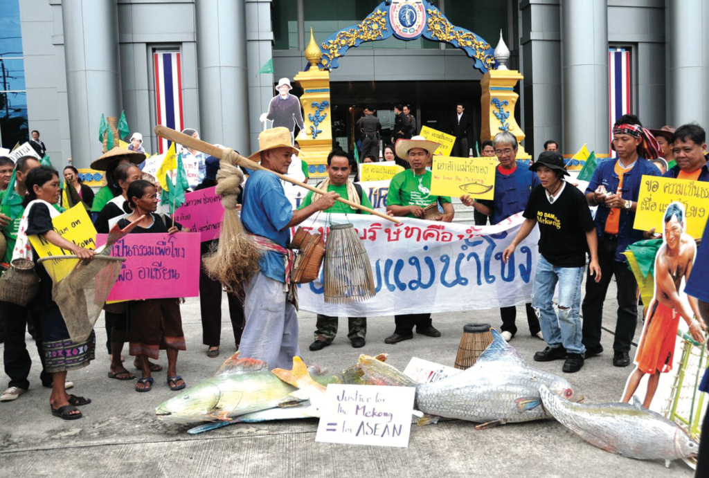A group of Thai people protesting with posters and prop fish. 