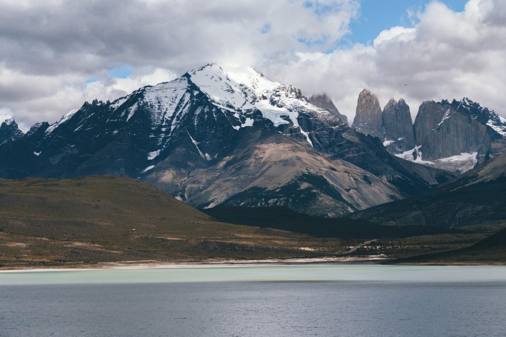 Ice capped mountains in the distance and the blue waters of lake Patagonia in the forefront. 