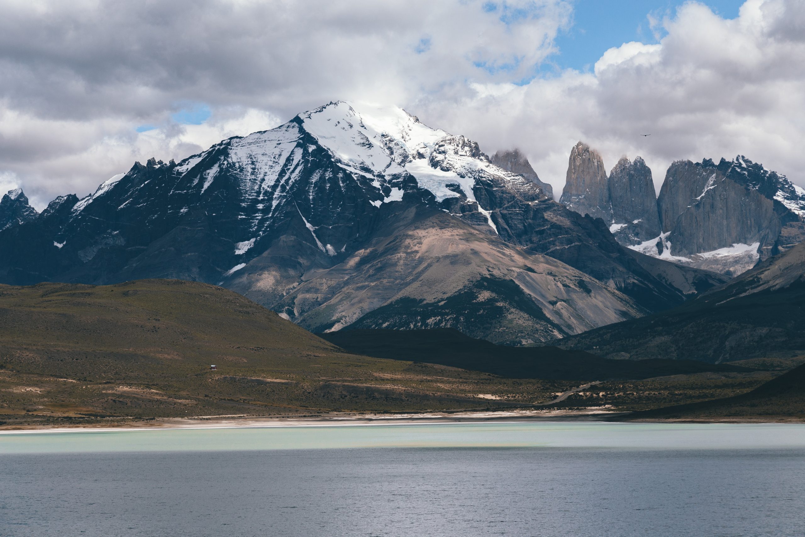 Ice capped mountains in the distance and the blue waters of lake Patagonia in the forefront.