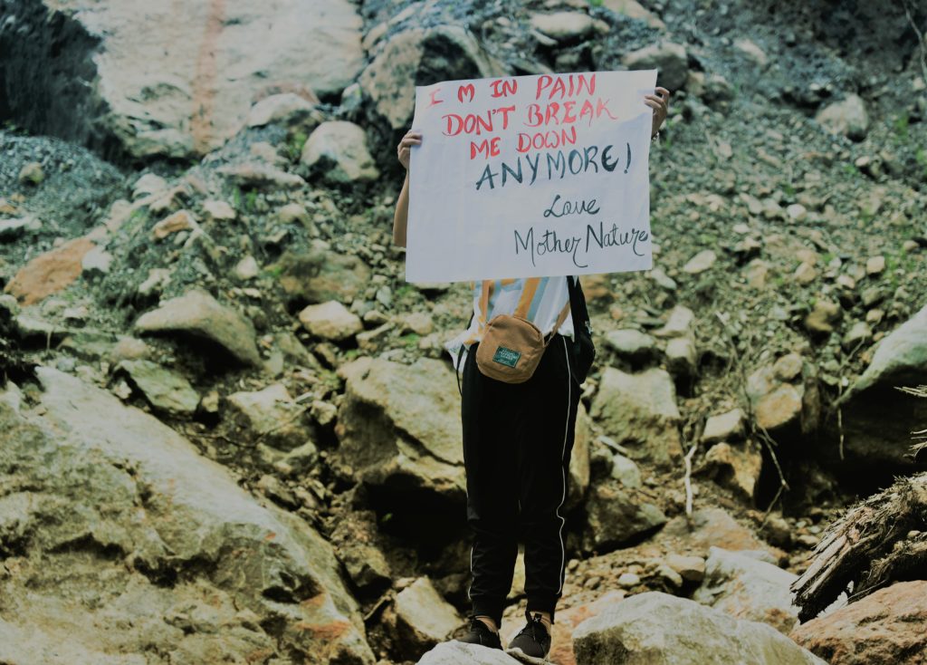 Protester in Upper Dzongu with sign reading "I am in pain. Don't break me down anymore. -Mother Nature"